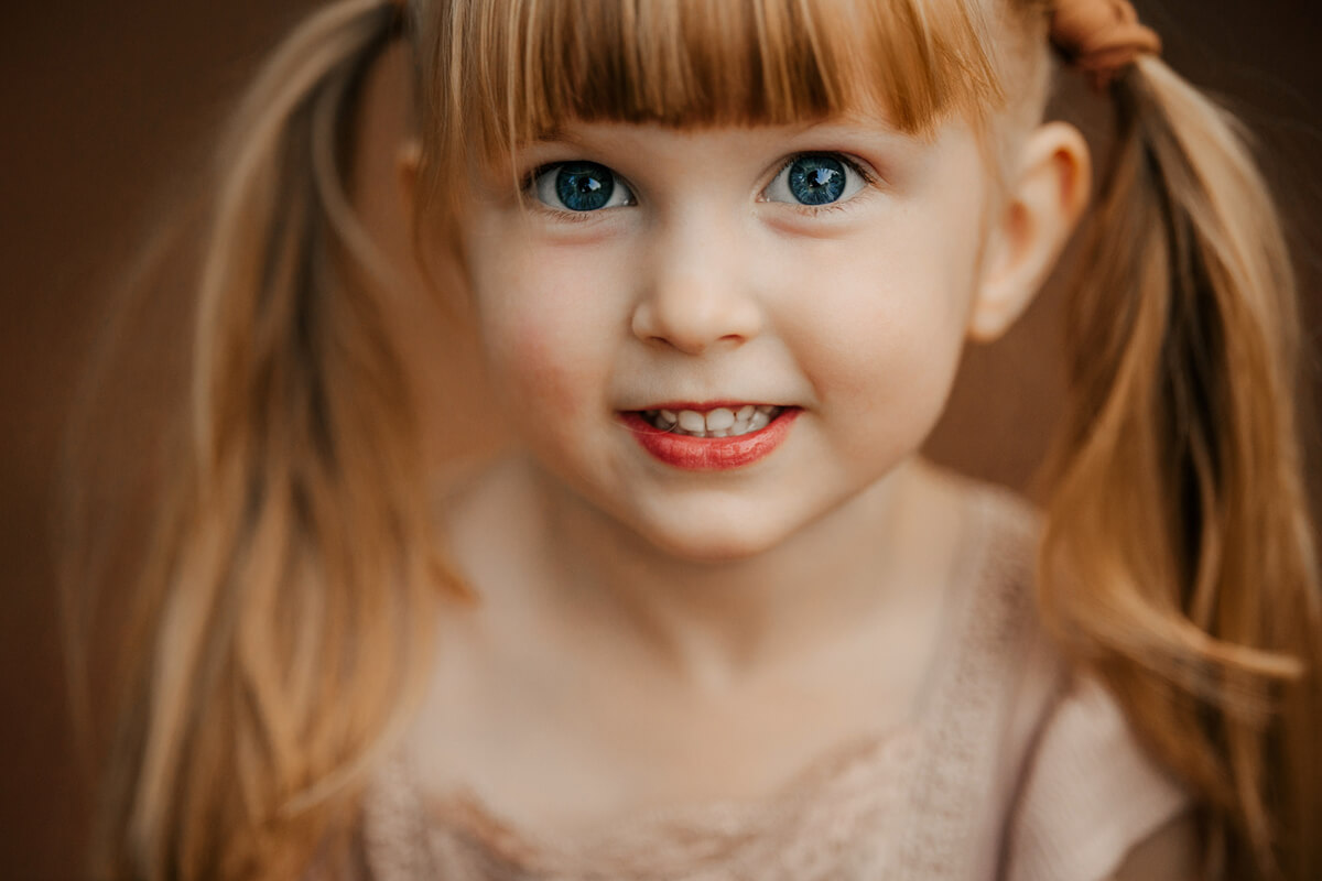 Young girl with blue eyes and pigtails smiling during candid child portrait session Grand Rapids Michigan GAUPERfamilies