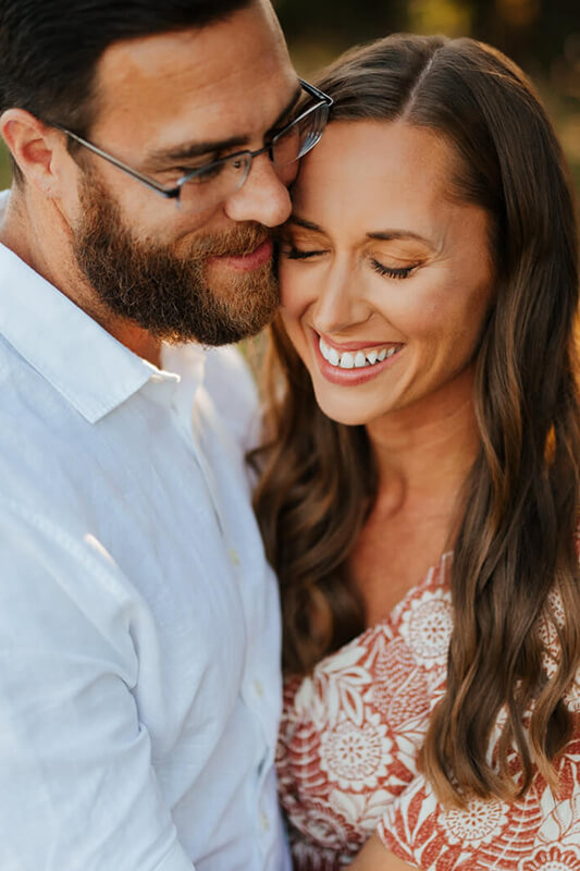 Couple sharing a tender forehead touch moment during candid family photography session Grand Rapids Michigan