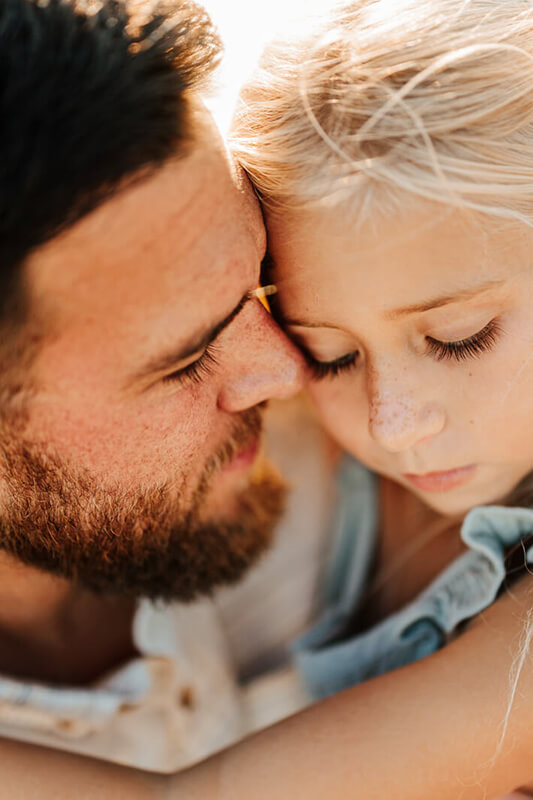 Father and young daughter sharing a quiet forehead to forehead moment during candid family photography session West Michigan