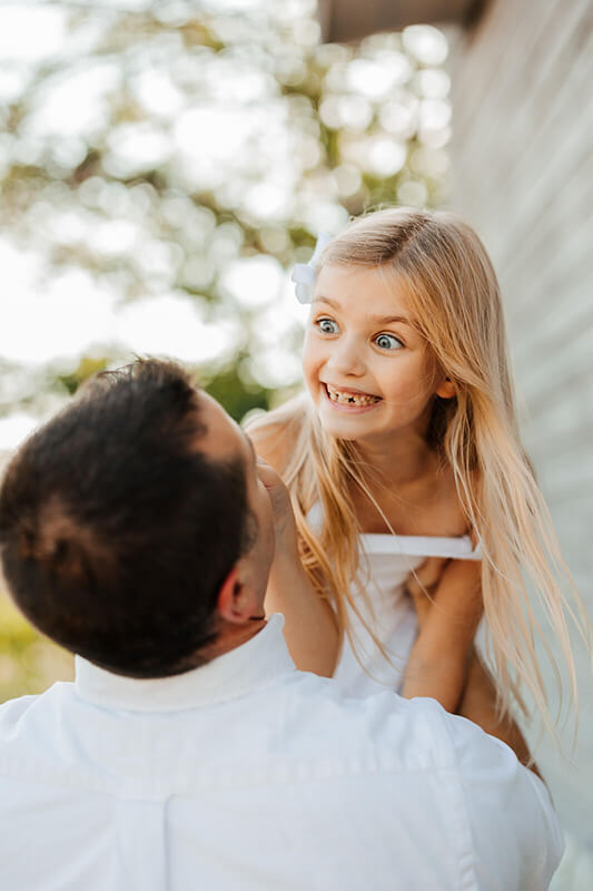 Father lifting laughing daughter during candid family photography session best West Michigan family photographer GAUPERfamilies